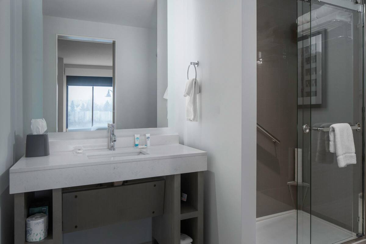 Een moderne badkamer met een grote spiegel, een wastafel en een douche met glazen wanden.