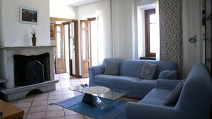 A living room with a fireplace, a blue sofa, and a glass coffee table. - Lakefront apartment in downtown Stresa with magnificent views (Stresa)