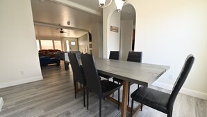 A dining area with a rectangular table and six chairs, a ceiling fan, and a view into a living room with a sofa and a coffee table. - Spacious Riverhouse with private park/boat ramp (Parker)