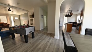 A spacious living area with a foosball table, a dining table, and a kitchen in the background. - Spacious Riverhouse with private park/boat ramp (Parker)