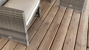 A covered porch with wicker furniture and a wooden deck. - Spacious Riverhouse with private park/boat ramp (Parker)