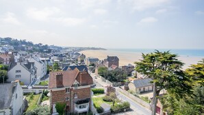 Een kustplaatsje met een combinatie van woongebouwen, een opvallend wit huis met balkon, en een strand op de achtergrond.