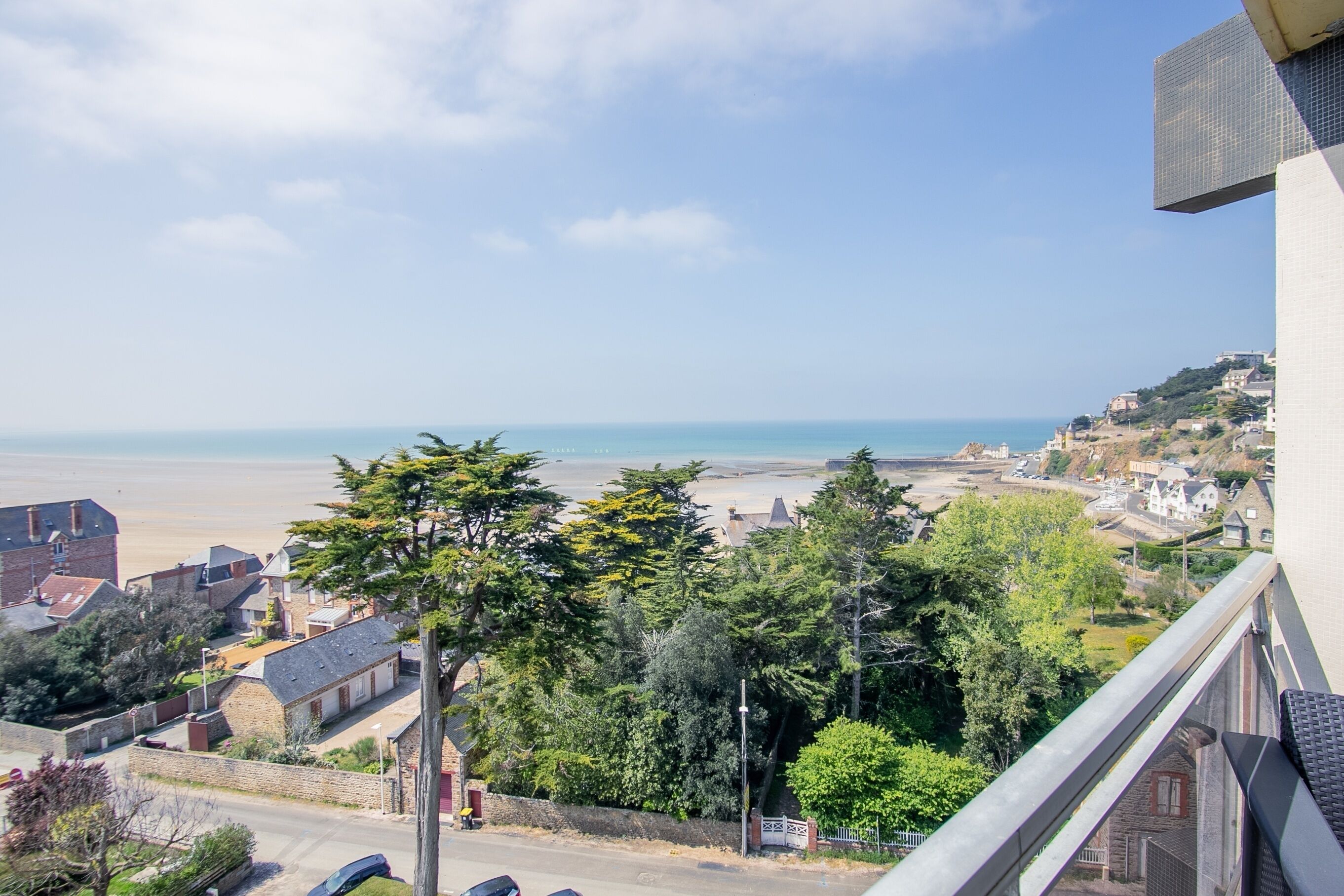 Une ville côtière avec une plage, des maisons et des arbres.