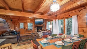 Een gezellig chalet binnen met een open haard, houten wanden, een eethoek en een televisie.