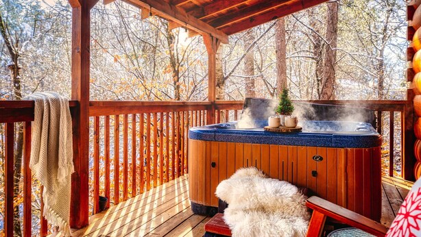 Een houten terras met een jacuzzi, een kleine kerstboom en een vachtkleed.