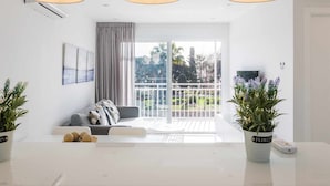 A modern living room with a sofa, a dining table, and a balcony with plants. - A&n Seafront Torre del Mar (Torre del Mar)