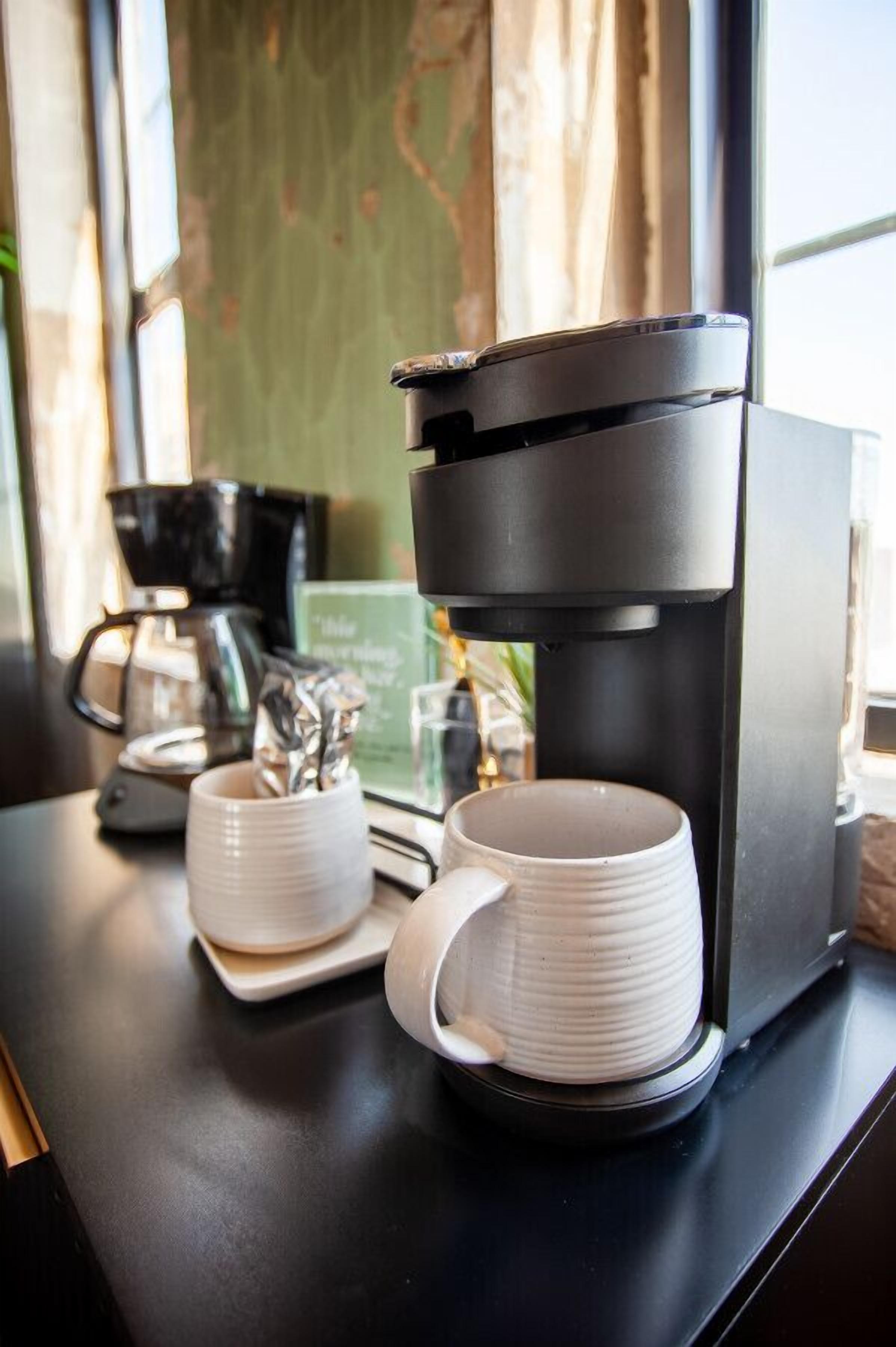 Una macchina per il caffè con due tazze bianche su un piano di lavoro nero.