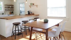 Una cocina moderna con una isla de madera, taburetes y luminarias colgantes.