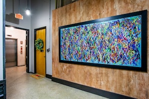 Stunning hallway with a large abstract painting, elevator, and door featuring a beautiful wreath.