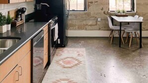 A kitchen with wooden cabinets, a black refrigerator, a dining table with chairs, and a bull's head decoration on the wall. - Modern Gay St Loft w/ View (Knoxville)