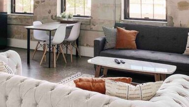 A spacious room with large windows, a sofa, a coffee table, and a dining area. - Modern Gay St Loft w/ View (Knoxville)
