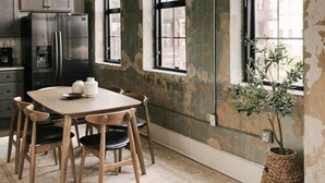 Een keuken met een grote tafel, stoelen, een koelkast en een potplant.