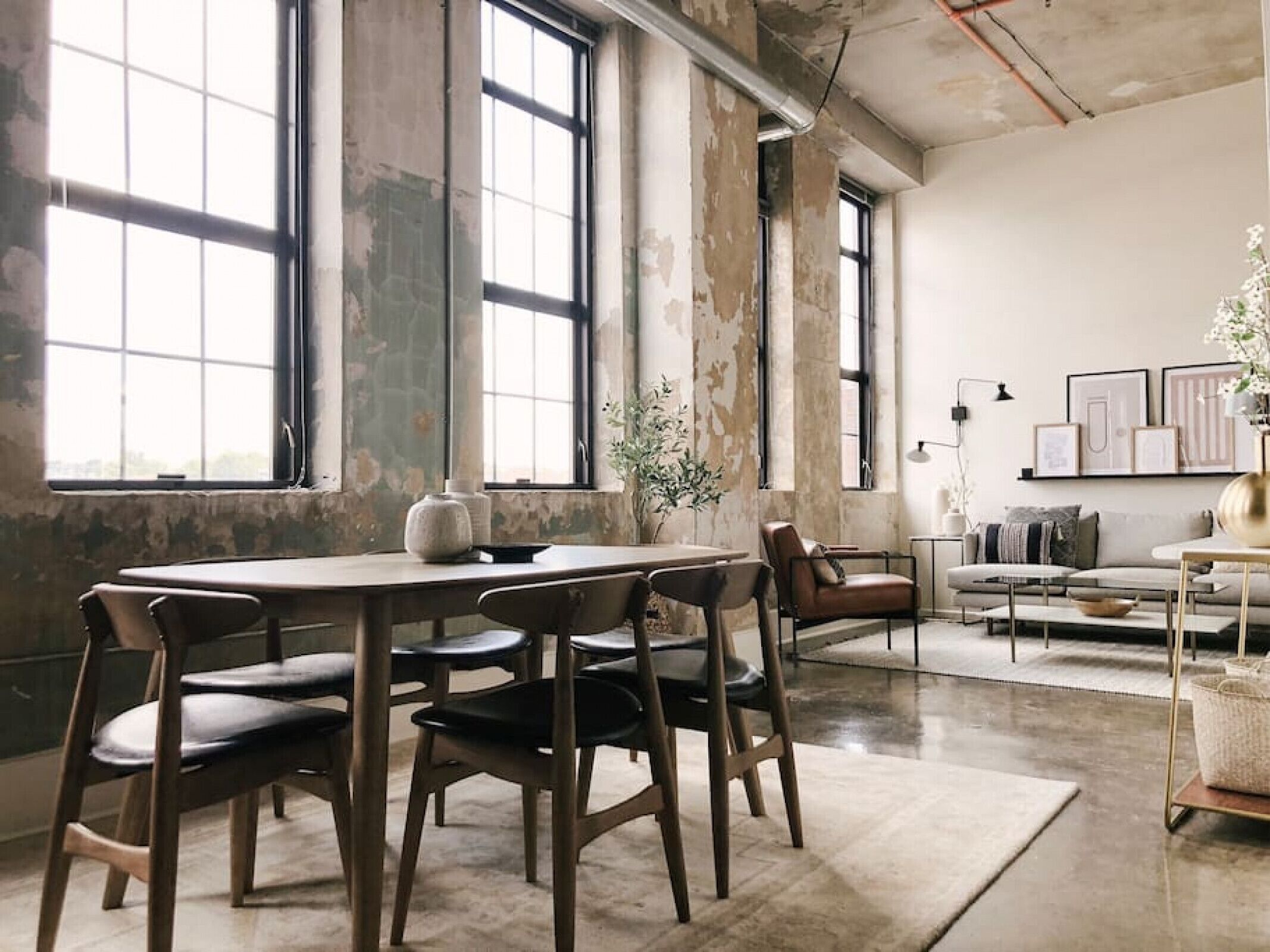 Um quarto espaçoso com janelas amplas, uma mesa de jantar com cadeiras, um sofá e uma mesa de centro.