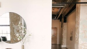 Een modern interieur met een minimalistisch design, met een ronde spiegel, een console tafel met decoratieve objecten, en een zithoek met een comfortabele fauteuil.