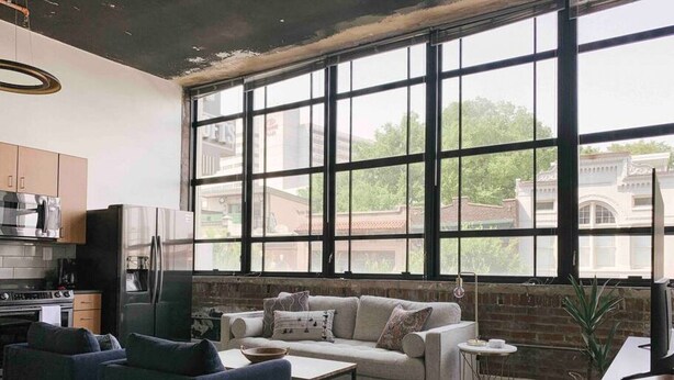 A modern kitchen with a large window, a sofa, and a coffee table.