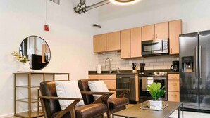 Una cocina moderna con armarios de madera, electrodomésticos de acero inoxidable y un espejo redondo en la pared.