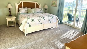 A bedroom with a bed, two bedside tables, a ceiling fan, a window with curtains, and a view of the outdoors. - Perfect Naples golf and beach getaway! Just minutes from downtown and beaches. (Naples)
