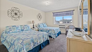 A bedroom with two beds, a dresser, a mirror, and decorative wall art.