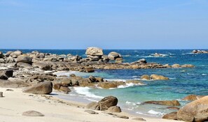 A rocky beach with large boulders and clear blue water.