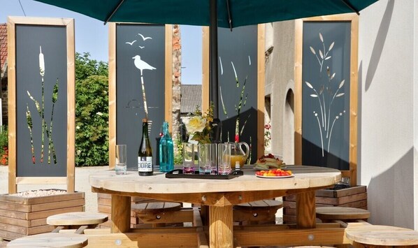 Een buiten eethoek met een ronde houten tafel, omringd door houten stoelen.