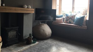 Uma sala de estar acolhedora com lareira, televisão, uma janela grande com vista e um espaço de estar confortável.