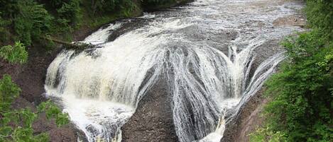A waterfall cascading over a rocky ledge surrounded by dense greenery.