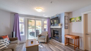 A living room with a sofa, a small table, a fireplace, and a television.
