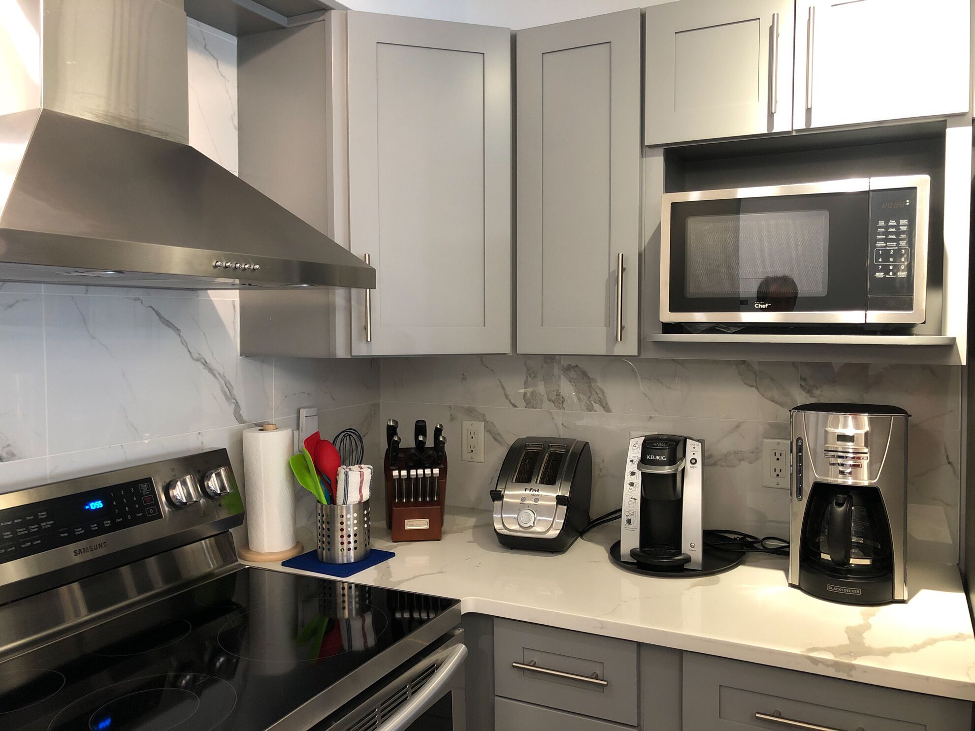 A modern kitchen with a stainless steel range, a microwave, a toaster, and a coffee maker.