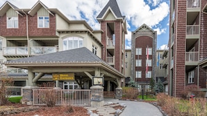 A hotel entrance with a covered walkway leading to the entrance, stone pillars, and a sign indicating the hotel's name and address.