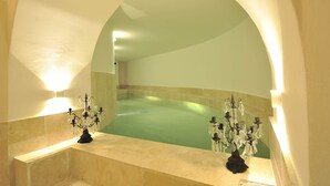 Ein Wellnessbereich mit einer großen Badewanne, zwei Kronleuchtern und einer Steinwand.