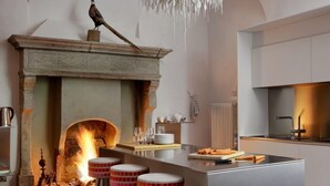 Eine moderne Küche mit einer zentralen Kochinsel, Barhocker, einem Kamin und einem Kronleuchter.