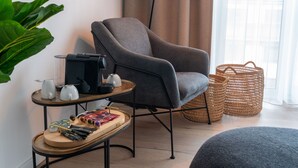 A modern living room with a grey armchair, a coffee table with tea sets, a floor lamp, and a large green plant. - Limehome Frankfurt Gutleutstraße (Frankfurt)