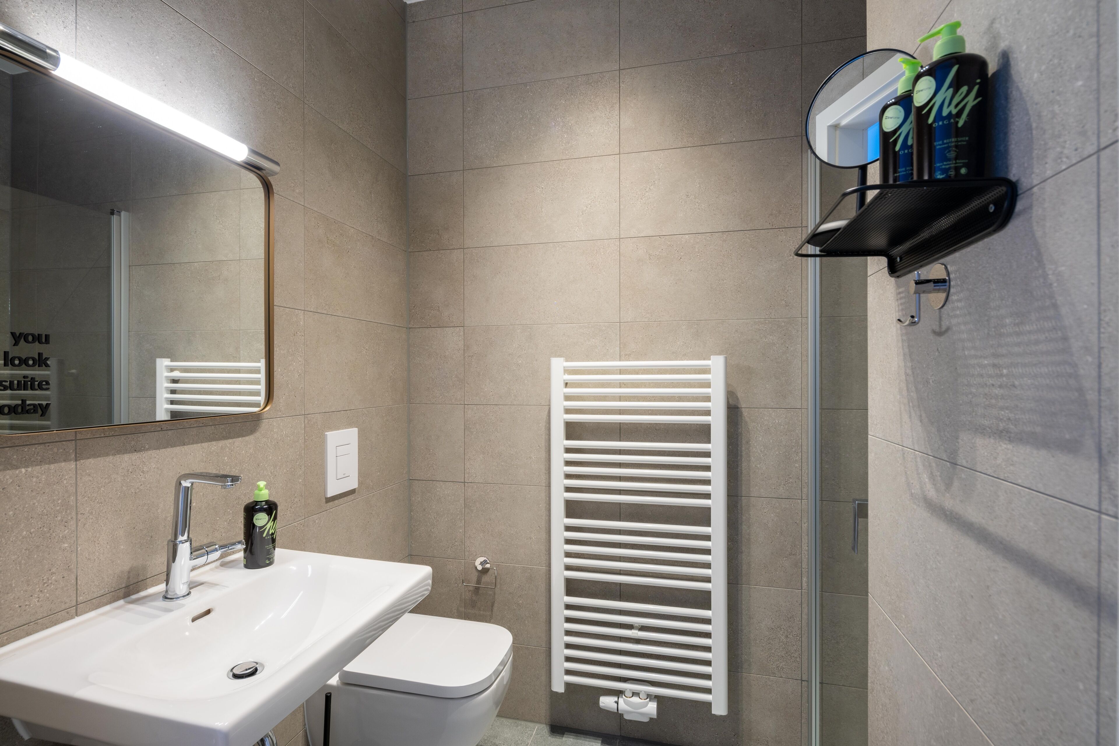 A bathroom with a white sink, a mirror, a towel rack, and a shower area.