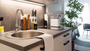 A modern kitchen with a stainless steel sink, wooden spice rack, and a white countertop. - Limehome Frankfurt Gutleutstraße (Frankfurt)