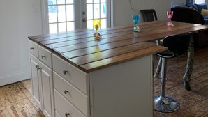 Una cucina con isola in legno, mobili bianchi e zona pranzo con tavolo e sedie.