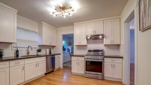 A modern kitchen with white cabinets, stainless steel appliances, and a wooden floor. - Fresh Modern Home in the Alberta Arts District! (Portland)