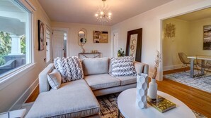 A modern living room with a grey sectional sofa, a round coffee table, and a dining area with a white table and chairs. - Fresh Modern Home in the Alberta Arts District! (Portland)