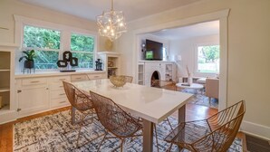 A modern kitchen with a white table, wicker chairs, and a geometric pendant light. - Fresh Modern Home in the Alberta Arts District! (Portland)