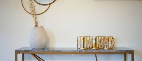 A marble console table with a gold-framed mirror and a decorative vase with dried plants.