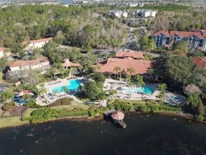 Ein Luftbild eines Resorts mit einem zentralen Schwimmbecken, mehreren Gebäuden und umliegender Vegetation.