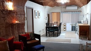 Una sala de estar acogedora con un sofá rojo, una mesita y un comedor con sillas y una mesa.