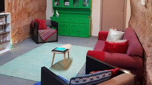 Una sala de estar acogedora con un sofá rojo, un aparador verde y una mesita.