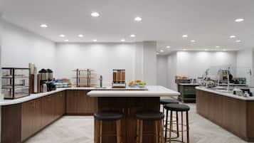 A modern kitchen with a central island, bar stools, and various kitchen appliances.