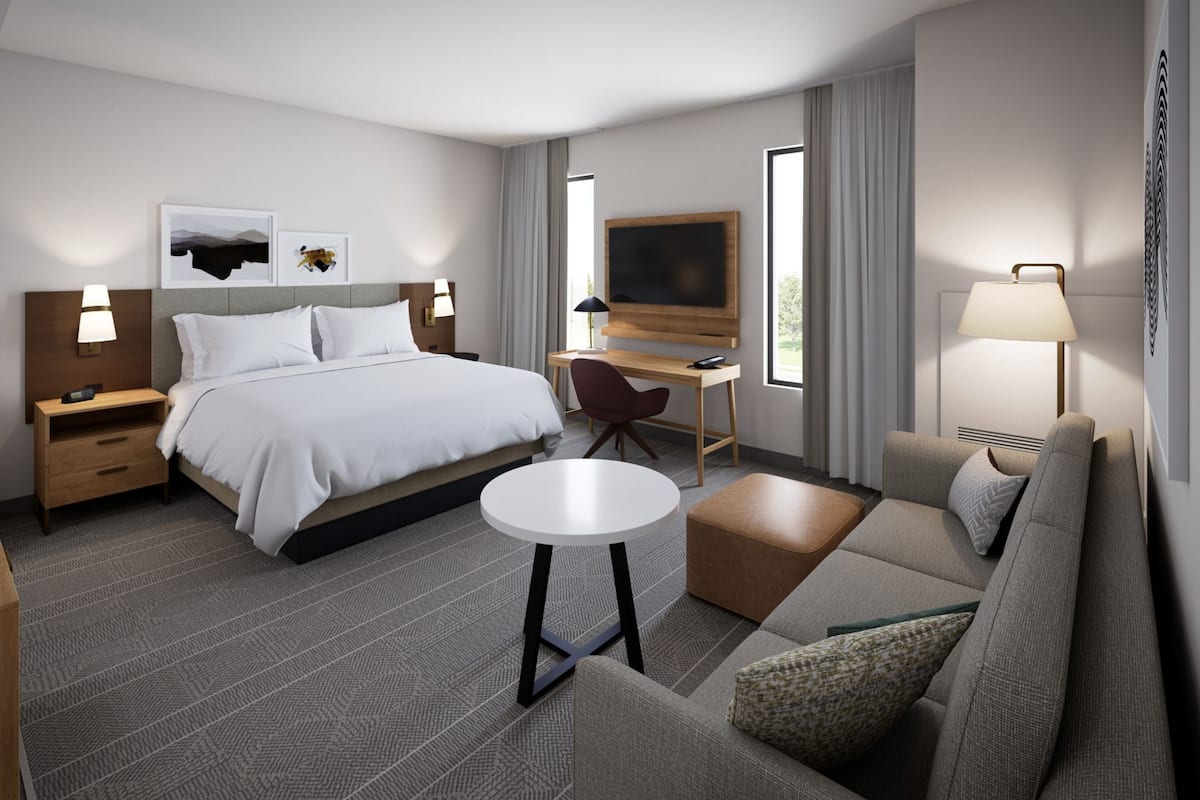 Een moderne hotelkamer met een bed, bureau, stoel, bank en een televisie.