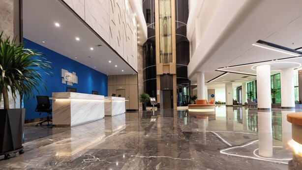 A modern lobby with a marble floor, a reception desk, and a blue accent wall. - Holiday Inn Express Harbin Exhibition Center by IHG (Harbin)