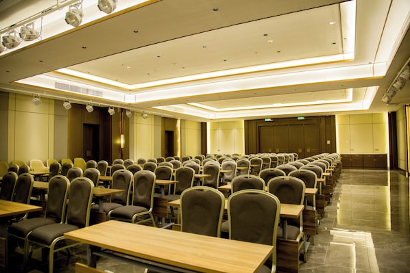 A conference room with rows of tables and chairs, a high ceiling with recessed lighting, and a polished floor. - Holiday Inn Express Harbin Exhibition Center by IHG (Harbin)