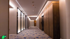 A hotel corridor with a patterned floor, wooden lockers, and a green exit sign. - Holiday Inn Express Harbin Exhibition Center by IHG (Harbin)