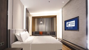 A modern hotel room with a large bed, a sofa, and a TV mounted on the wall. - Holiday Inn Express Harbin Exhibition Center by IHG (Harbin)