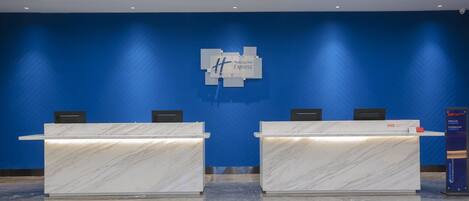 A reception area with two marble reception desks, a blue wall with a Holiday Inn Express logo, and a blue wall with a herringbone pattern.