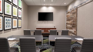 A conference room with a large table, six chairs, a flat-screen TV, and a patterned carpet. - Holiday Inn Express & Suites Bullhead City by IHG (Bullhead City)